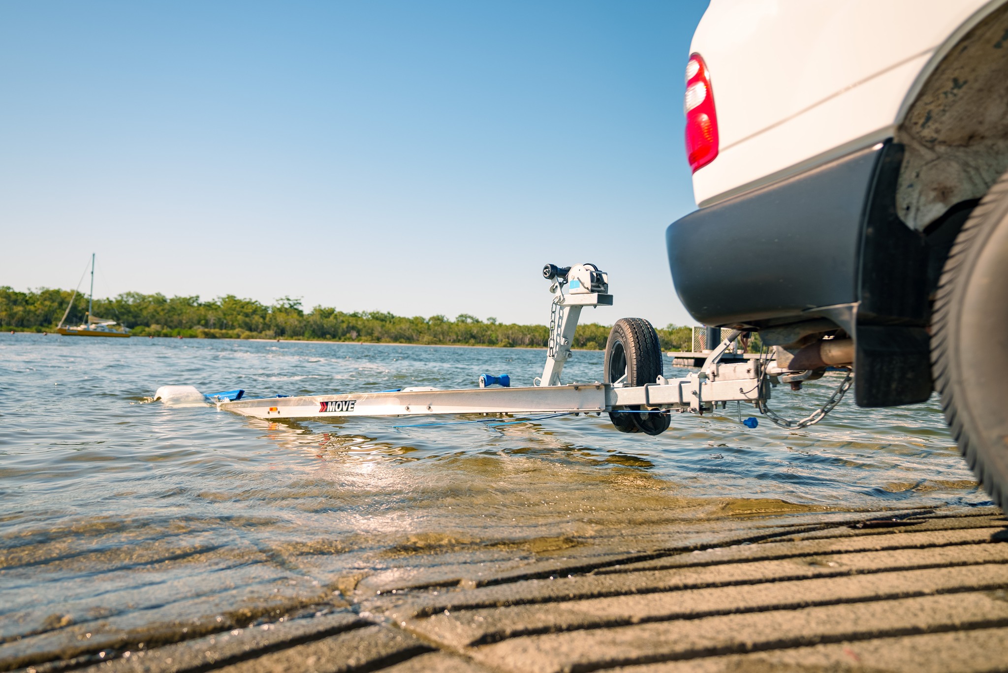 A boat on a trailer being pulled away from the water's edge, with a winterization kit and equipment visible in the foreground